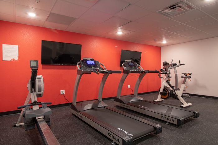 Fitness center with multiple workout machines and two TVs