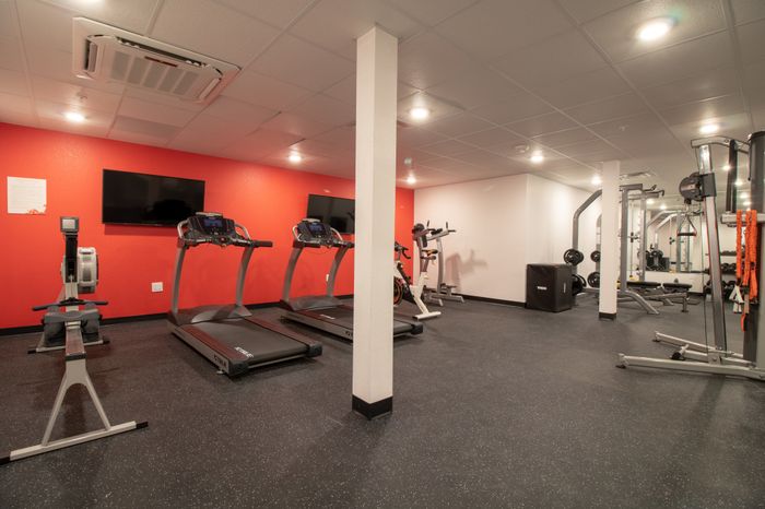 Fitness center with multiple workout machines, free weights and two TVs