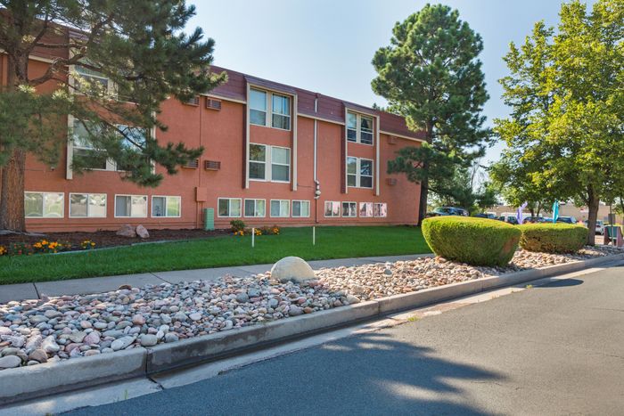 Street view of building with grassy area and trees