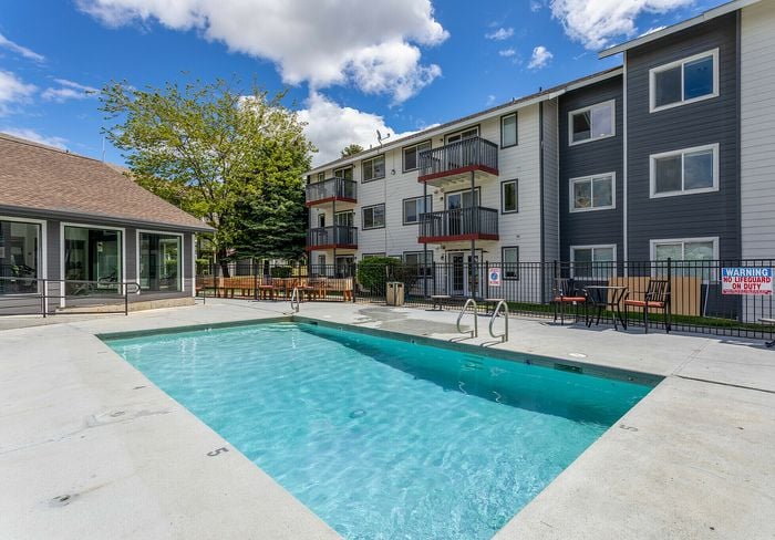 Inviting outdoor pool area with stylish apartment building featuring balconies.