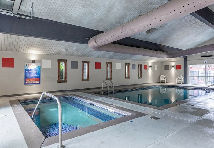 Modern indoor swimming pool with jacuzzi, stylish lighting, and colorful wall accents creating a relaxing ambiance.