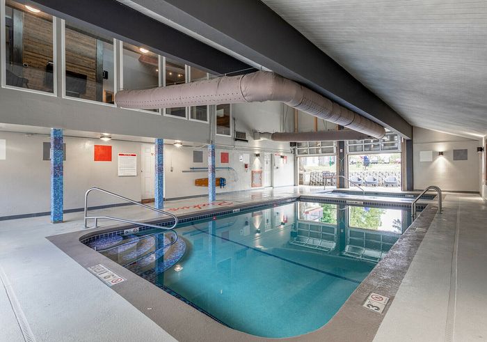 Modern indoor swimming pool with elegant design, featuring large windows and ample lighting.