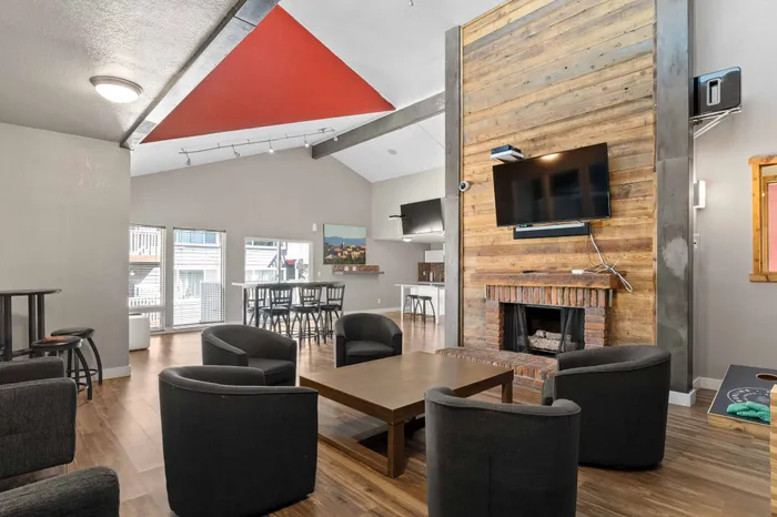Modern communal living area featuring chic seating, a rustic fireplace, and a vibrant red ceiling accent.