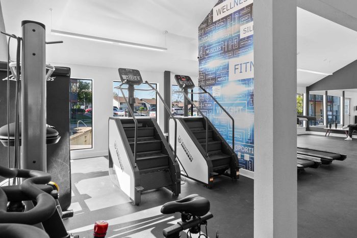 Modern fitness center with state-of-the-art stair climbers, inspiring motivational wall, and floor-to-ceiling windows providing natural light.