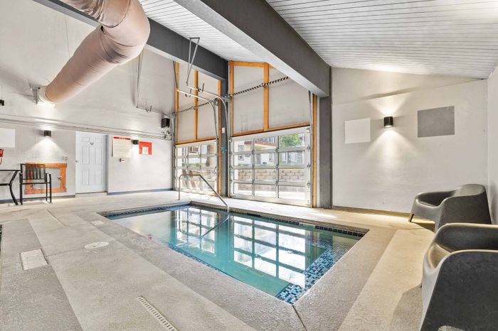 Inviting indoor pool area with natural light, modern seating, and stylish lighting.