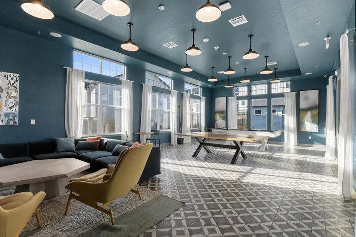 Spacious, well-lit lounge area featuring modern furniture and a sleek ping pong table.