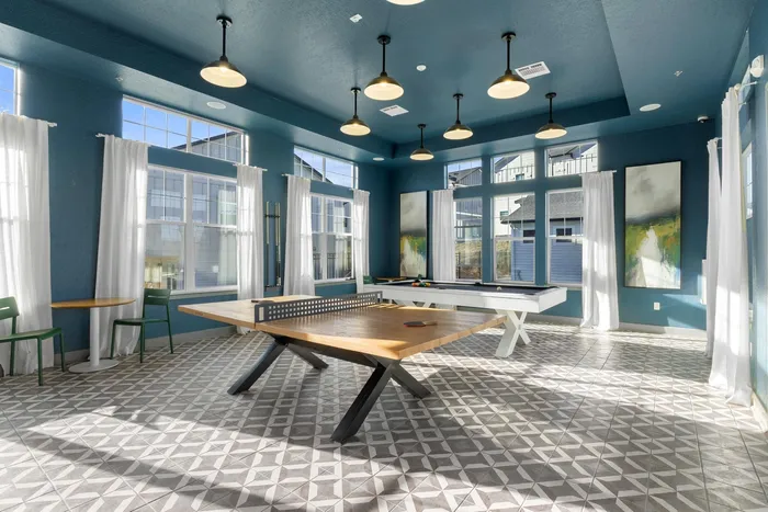 Stylish game room with table tennis and pool table, featuring elegant lighting and large windows.