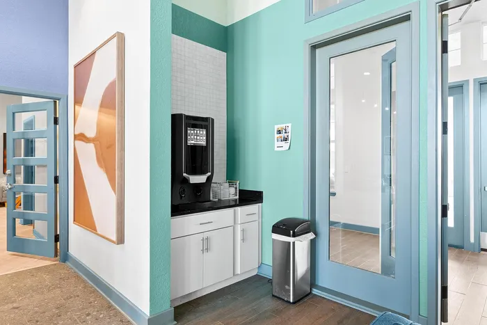 Modern corner coffee station with sleek cabinetry, teal accents, and a contemporary coffee machine.
