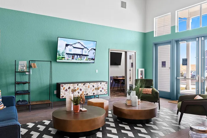 Bright and welcoming lounge area with stylish furniture, green accent wall, and large windows.