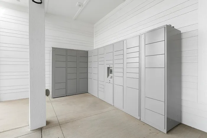 Modern package room with sleek, grey lockers and clean white walls.