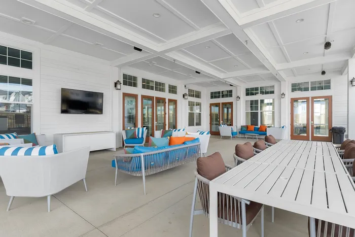Spacious outdoor lounge area with colorful seating, featuring modern decor and a wall-mounted TV.