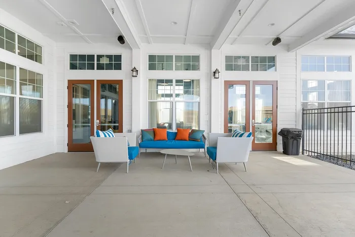 Stylish outdoor seating area featuring modern chairs and colorful cushions against a backdrop of elegant French doors.
