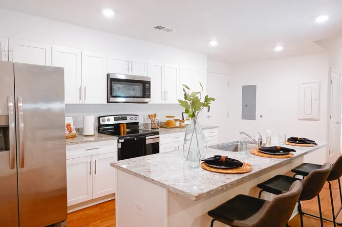 Modern kitchen with sleek stainless steel appliances, elegant marble countertops, and a stylish breakfast bar adorned with chic place settings.