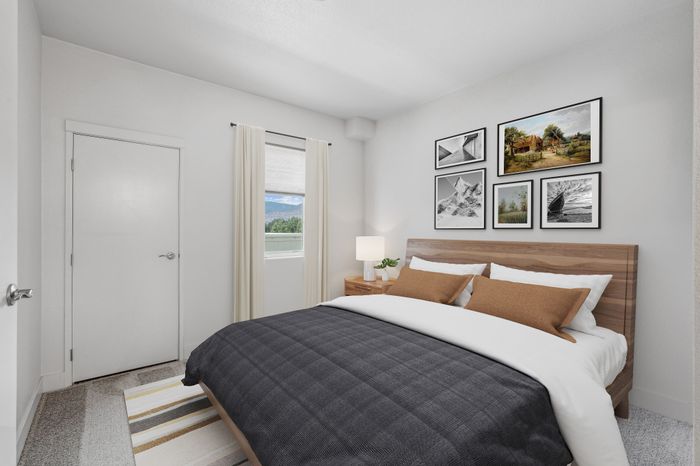 Bright and modern bedroom featuring a wooden bed with plush bedding, stylish wall art, and a scenic window view.