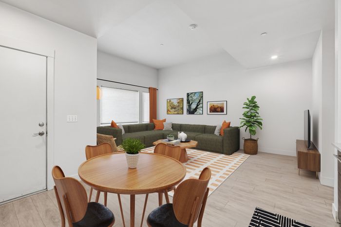 Modern living space with a cozy sectional sofa, stylish decor, and dining area. Bright ambiance with a large window and vibrant artwork enhancing the spacious room.