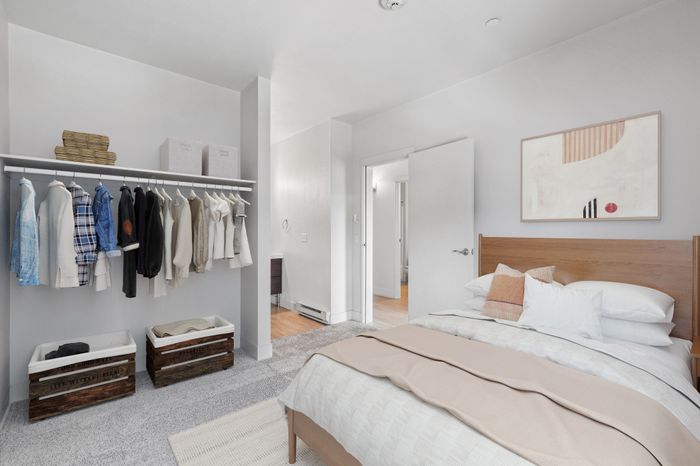 Contemporary bedroom with cozy bedding, stylish artwork, and an organized open closet that enhances the modern aesthetic.