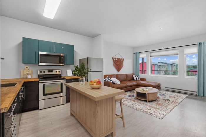Modern open-concept kitchen and living space featuring sleek cabinetry, stainless steel appliances, and a cozy seating area with a stunning view from large windows.