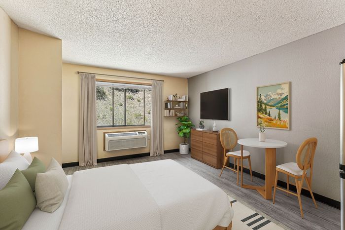 Inviting bedroom with stylish decor, featuring a cozy bed, modern wall art, and a picturesque view through a large window.