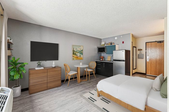 Modern studio apartment with stylish decor, featuring a cozy bed, elegant dining area, sleek kitchenette, and contemporary furnishings.