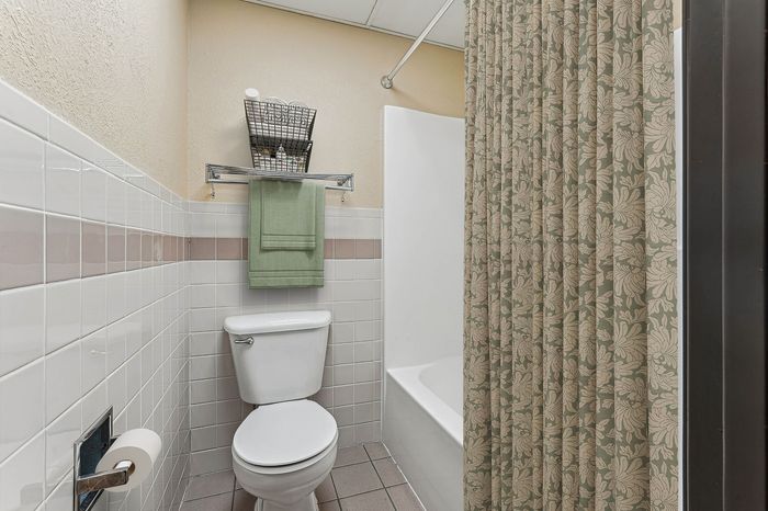 Elegant bathroom featuring pristine white tiles, chic patterned shower curtain, and stylish towel rack for a modern touch.