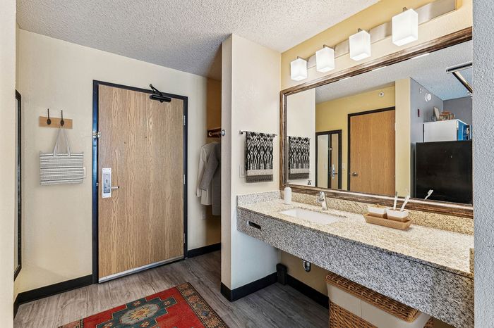 Chic and inviting bathroom with elegant granite countertop, large mirror, and modern lighting fixtures.