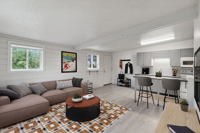 Modern open-concept living area with cozy seating, vibrant wall art, and chic kitchen in a stylish apartment.