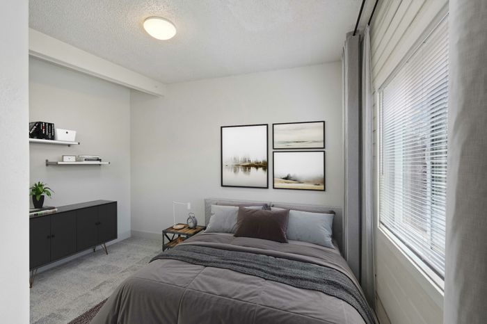 Modern bedroom with sleek decor, featuring a plush bed, stylish wall art, and ample natural light from the window.