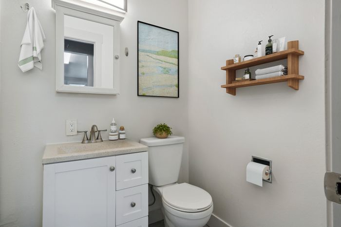 Chic bathroom with modern white vanity, elegant mirror, and stylish wooden shelf for storage.