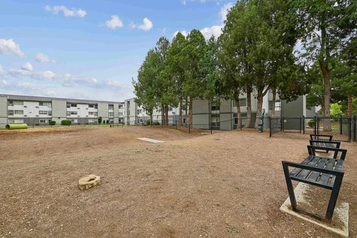 Beautiful apartment complex with a serene outdoor area featuring lush green trees and modern architecture.