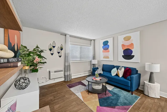 Chic living room with vibrant decor, featuring a blue sofa, colorful geometric rug, and modern wall art, perfect for urban living.