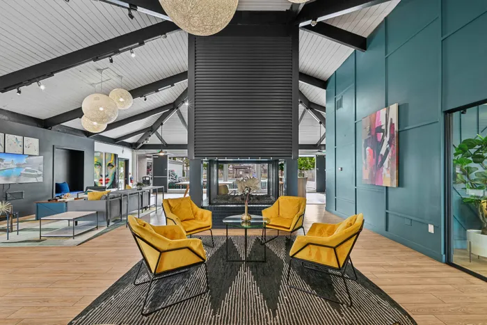 Modern lobby with chic yellow armchairs, stylish decor, and vibrant artwork under vaulted ceilings.
