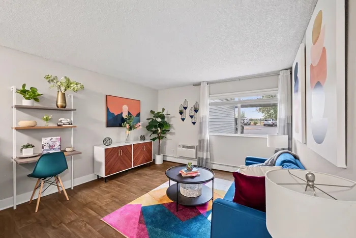 Chic and modern living room with vibrant accents, featuring a cozy blue sofa, colorful geometric rug, and stylish wall art.