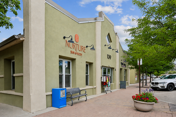 Charming street view of a skin and body care shop with an inviting exterior, potted flowers, and convenient parking.