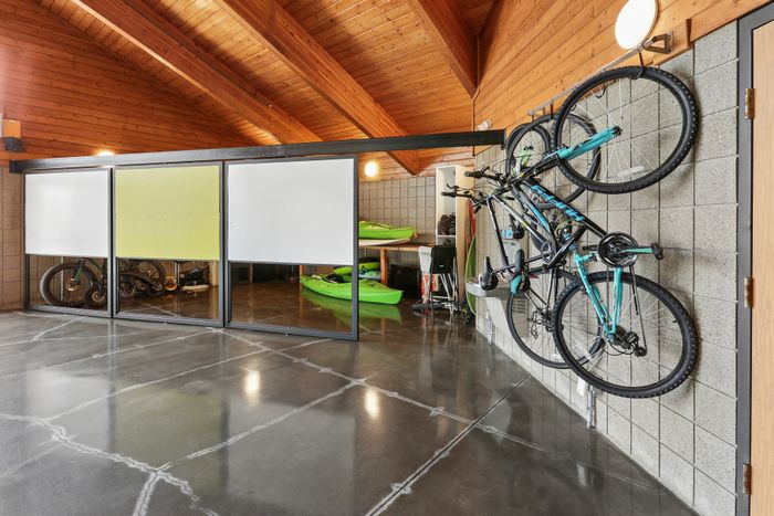 Modern garage with shiny concrete floors, wall-mounted bicycles, and kayaks, showcasing versatile storage solutions.