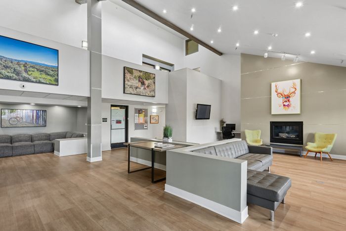 Elegant, modern living space with high ceilings, cozy seating, and vibrant artwork, perfect for relaxation and socializing.