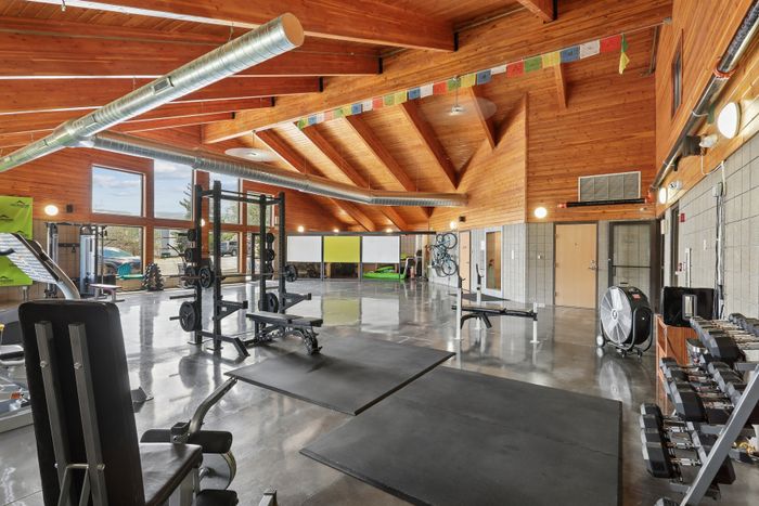 Spacious and modern gym with high ceilings, featuring state-of-the-art fitness equipment and natural lighting.
