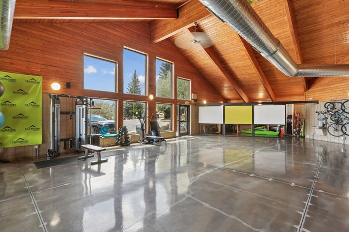 Expansive fitness area with high wooden ceilings and modern gym equipment in a sunlit, airy space.