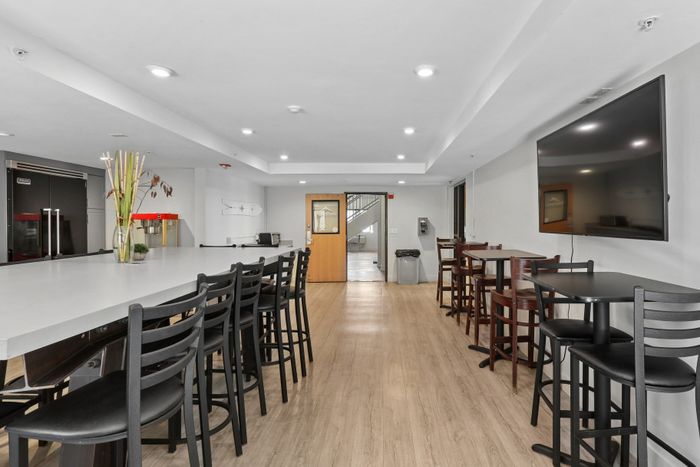 Modern communal area with sleek high-top seating and large TV, perfect for gatherings and relaxation.