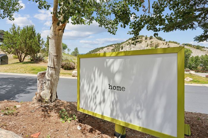 Inviting outdoor view with 'home' sign nestled among lush greenery and scenic mountain backdrop, perfect for tranquil living.