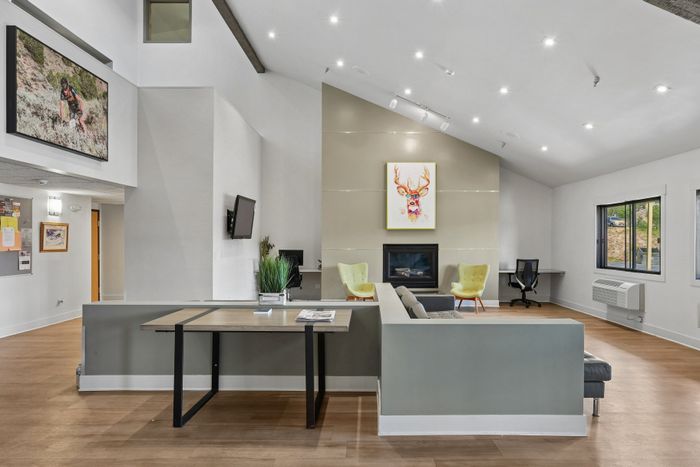 Modern, spacious living area with high ceilings, sleek fireplace, colorful art, and stylish furniture.
