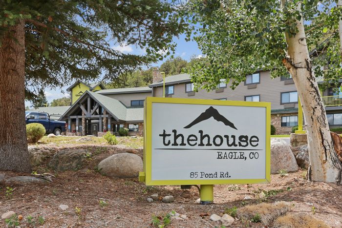 Charming exterior of The House in Eagle, CO surrounded by lush greenery and welcoming signage at 85 Pond Rd.