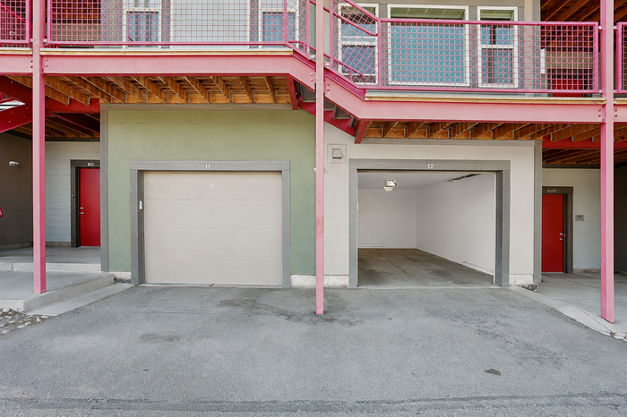 Contemporary apartment exterior featuring vibrant red and green accents with garage parking and modern architectural design.