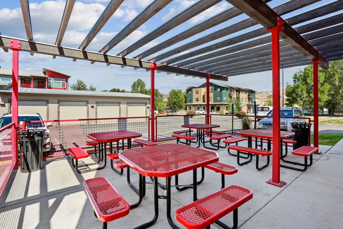 Vibrant outdoor patio area with red picnic tables under a stylish pergola, perfect for gatherings and enjoying sunny days.
