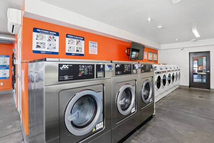 Modern laundry room featuring high-efficiency washers and vibrant orange accent walls, creating a bright and efficient space.