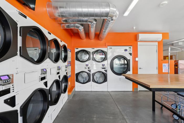 Modern laundry room with vibrant orange accents, featuring efficient stacked washers and dryers, ideal for urban living.
