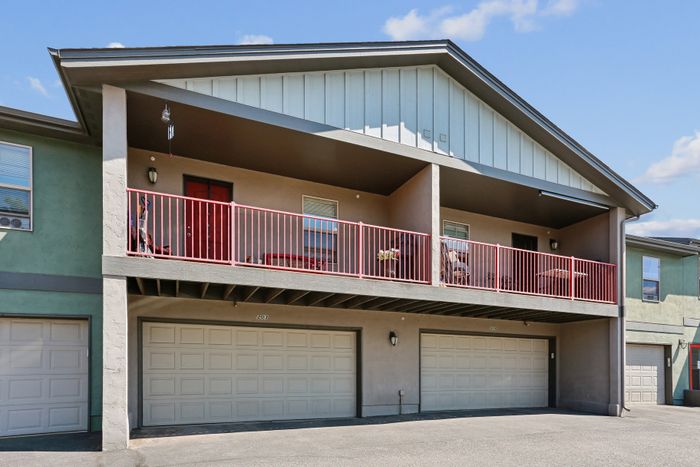 Charming two-story apartment with a spacious balcony, dual garages, and a modern exterior design.