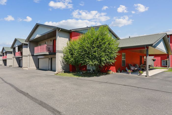 Charming apartment building featuring vibrant red exteriors, private balconies, and welcoming outdoor seating area.