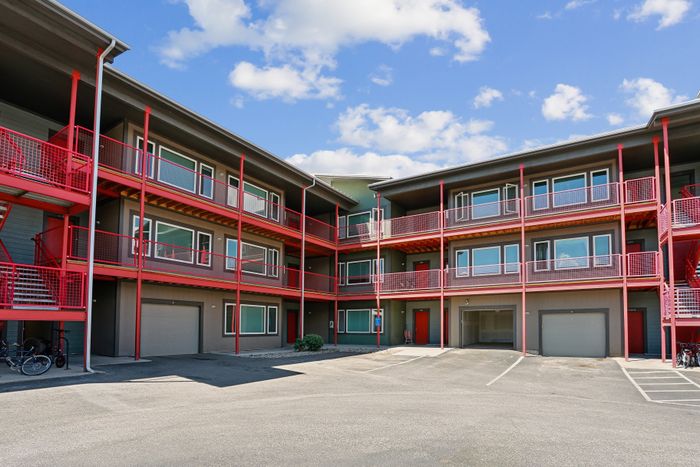 Vibrant and modern apartment building with striking red balconies, showcasing contemporary architecture against a bright blue sky.