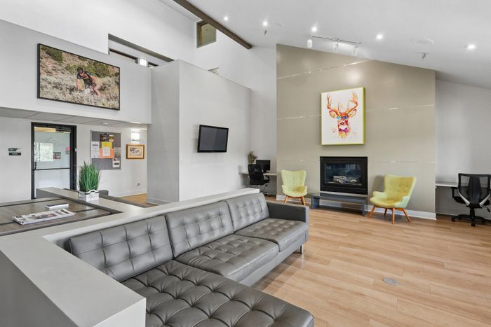 Modern lounge area with sleek gray sofa, vibrant artwork, and cozy fireplace, perfect for relaxation and social gatherings.