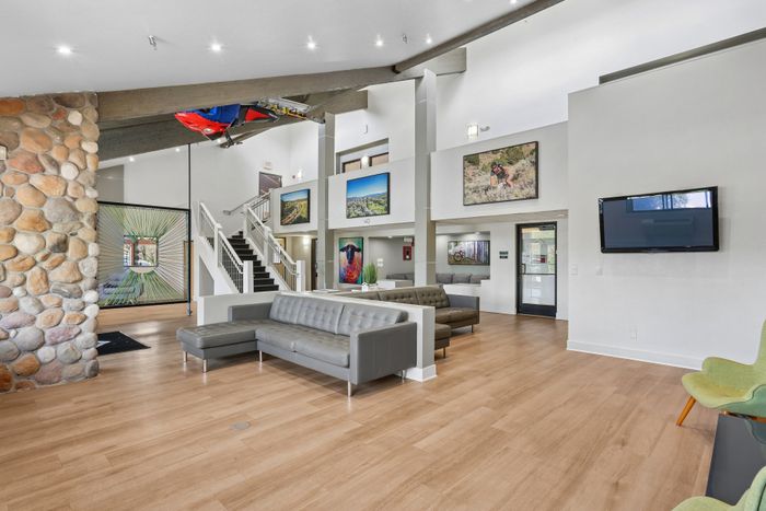Modern lobby area featuring sleek gray sofas, a stone accent wall, artistic d&eacute;cor, and vibrant photographs, all under bright recessed lighting.
